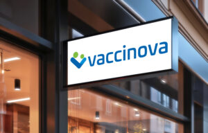 Vaccinovas ingång. Bilden visar en skylt med vit bakgrund oxh vaccinovas logga. Skylten är placerad på fasaden till en mottagning med skyltfönster under.